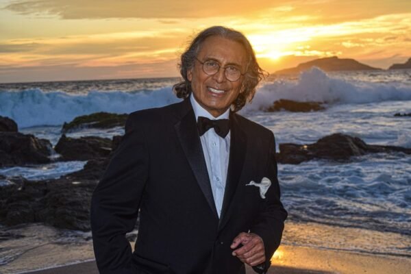 King Clave posando frente a la playa con el mar de fondo, mostrando una expresión relajada y elegante.