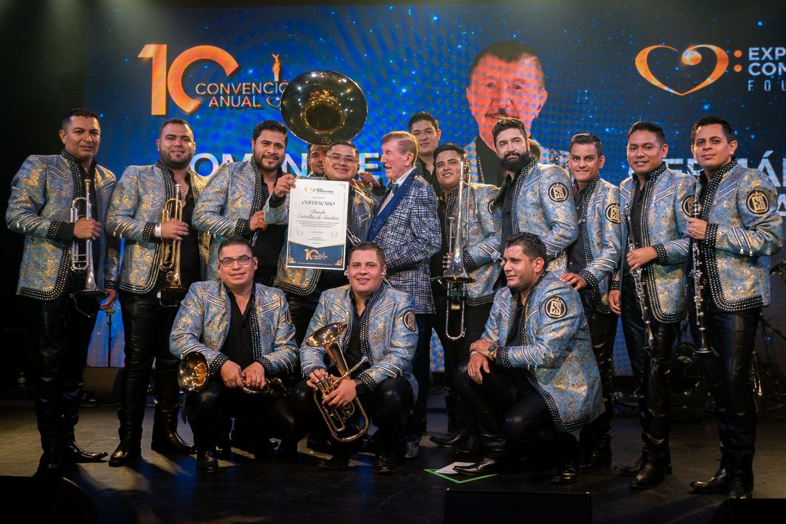 Germán Lizárraga de pie en el escenario del Lunario del Auditorio Nacional, sosteniendo un reconocimiento honorífico, rodeado de aplausos durante su homenaje en Expo Compositores 2025.