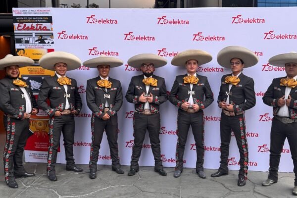 El Mariachi Los Gavilanes de José Alfredo Jiménez posa en el escenario durante la celebración del 75 aniversario de Elektra, junto a los colores y emblemas de Grupo Salinas.